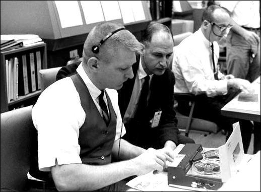 Flight director for the Gemini VII white team, Eugene F. Kranz (left), and George M. Low, Manned Spacecraft Center deputy director, ready a transmission tape from NASA's Gemini VII spacecraft which was received on December 9, 1965.