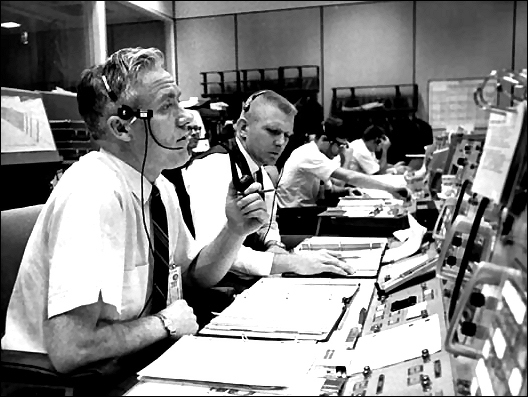 Gemini VIII Flight Directors John D. Hodge (left) and Eugene F. Kranz at their console in the Mission Control Room at the Manned Spacecraft Center during the critical reentry maneuver of the Gemini VIII spacecraft into the Earth's atmosphere which occurred on March 16, 1966.