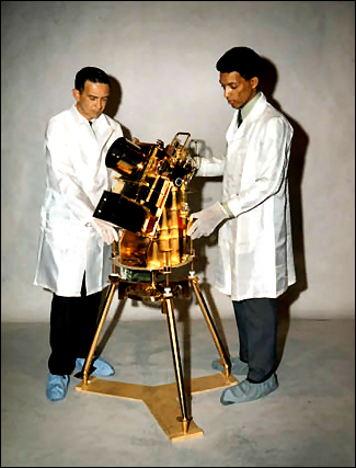 Above: Dr. George R. Carruthers, right, and William Conway, project manager at the Naval Research Institute, examine the lunar surface far-ultraviolet camera.