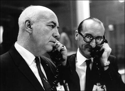 Dr. Robert Gilruth (left), director of the Manned Spaceflight Center, and Dr. George Mueller, NASA associate administrator of manned space flight, talk by phone with NASA Administrator James E. Webb and Dr. Robert C. Seamans, Jr., NASA associate administrator at NASA Headquarters.